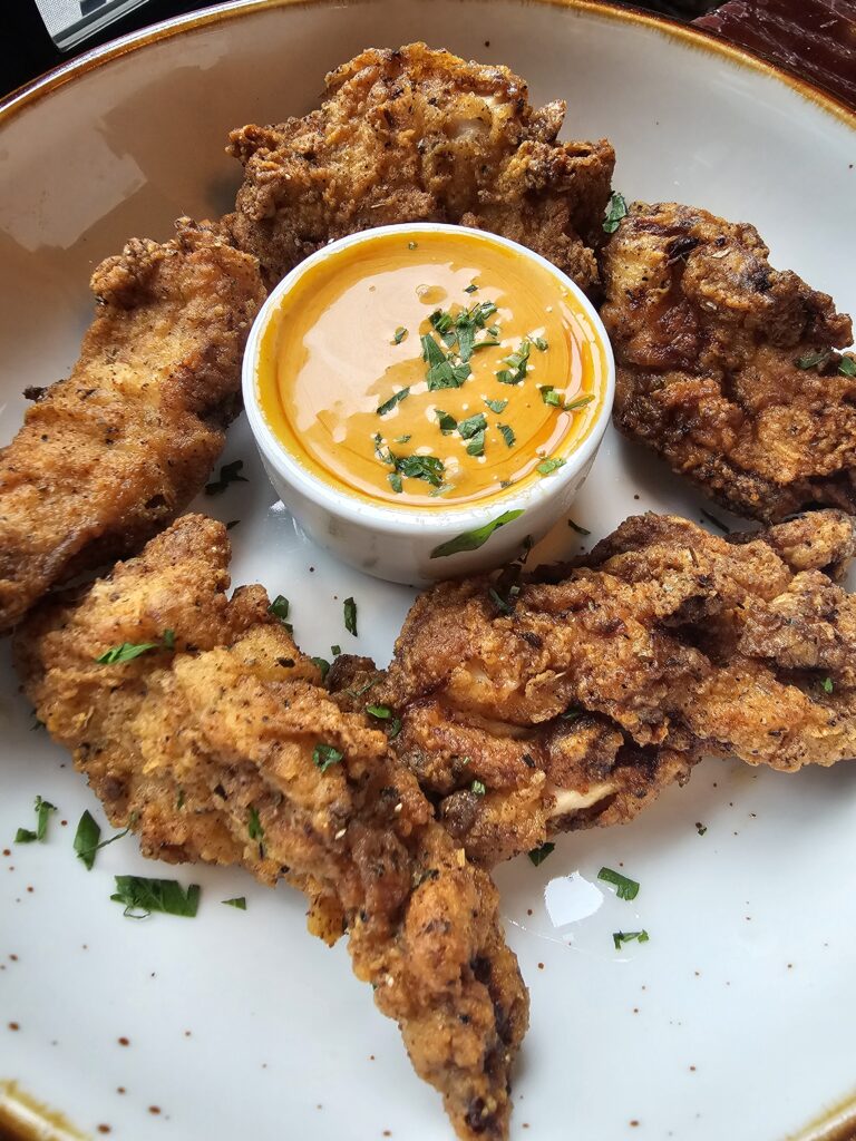 Crispy fried chicken strips with hot honey dipping sauce at Camp West