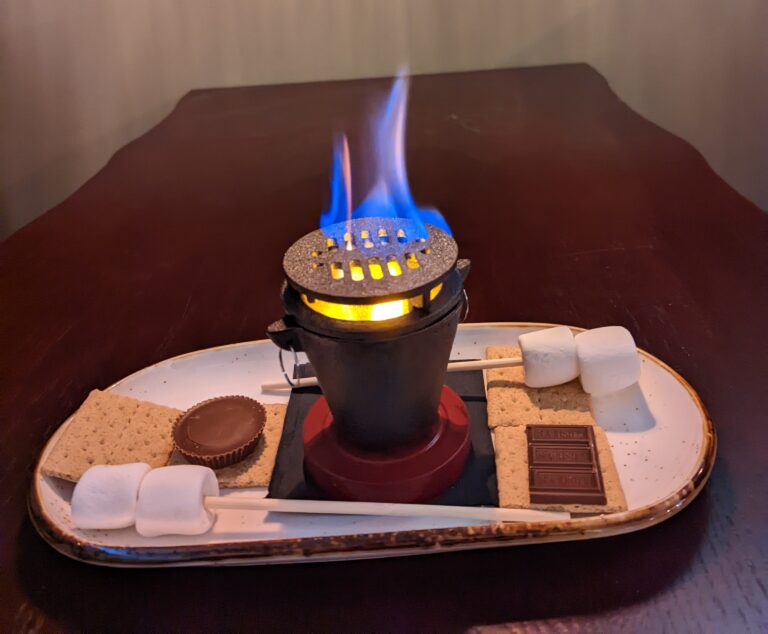 Tabletop s'mores kit at Camp West with a flame, marshmallows, graham crackers and chocolate